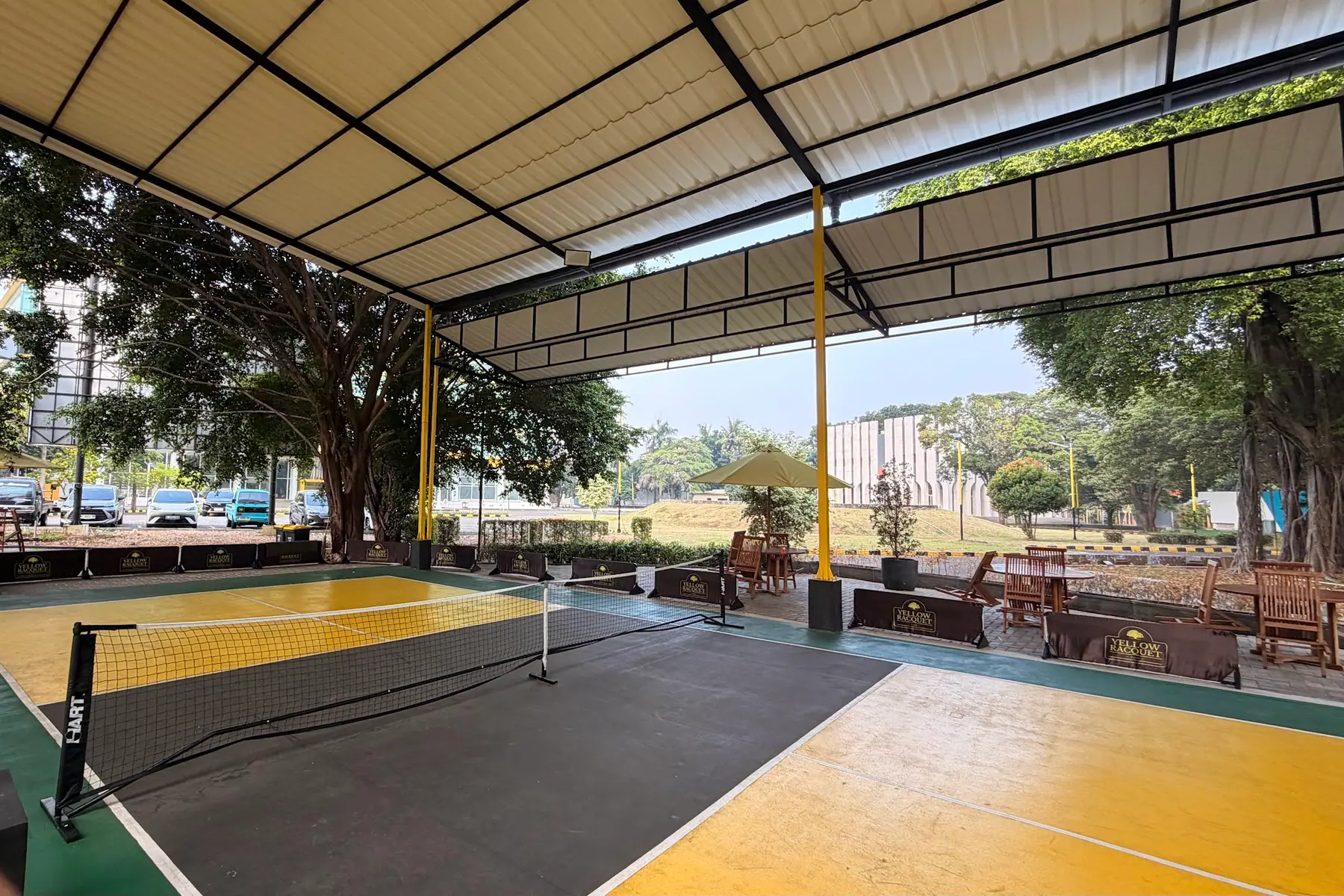 Pickleball court with a yellow and black surface under the roof